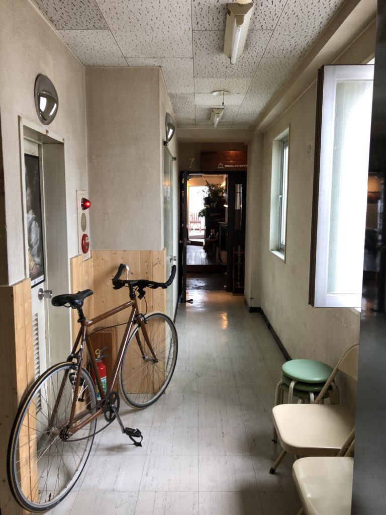 自転車のある廊下の向こうにカフェがある